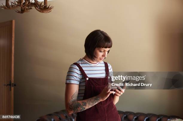 young woman in her living room texting - bang palabra en inglés fotografías e imágenes de stock