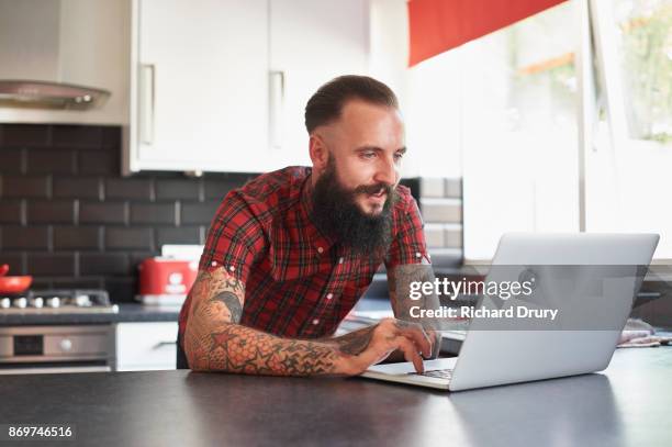 young man using laptop on his kitchen - hipster in a kitchen stock-fotos und bilder