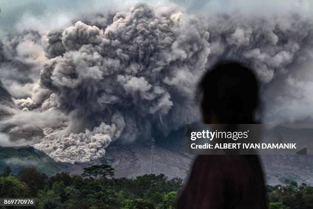 An Indonesian woman watches an eruption from the Mount Sinabung volcano from Tiga Pancur village, in Karo in North Sumatra on November 3, 2017. -...