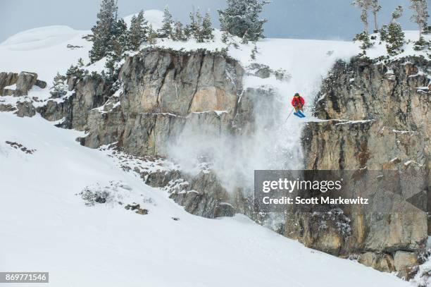 a man jumping off a cliff while skiing powder snow on a sunny winter day - alta stock-fotos und bilder