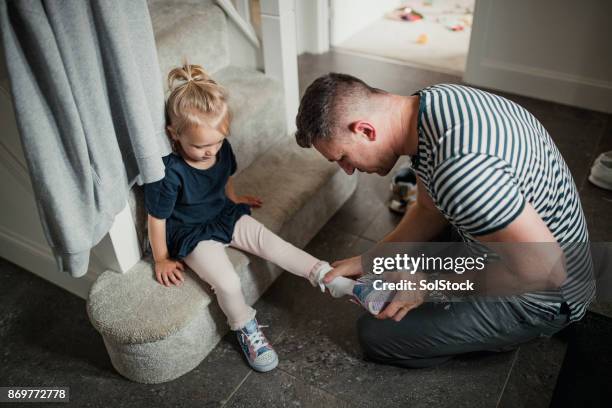 putting his daughters shoes on - putting shoes stock pictures, royalty-free photos & images