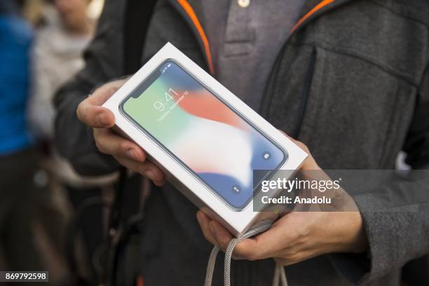 Chris Rotella holds up his brand new iPhone X after being of the first people to emerge from the Georgetown Apple Store with it in Washington, USA on...