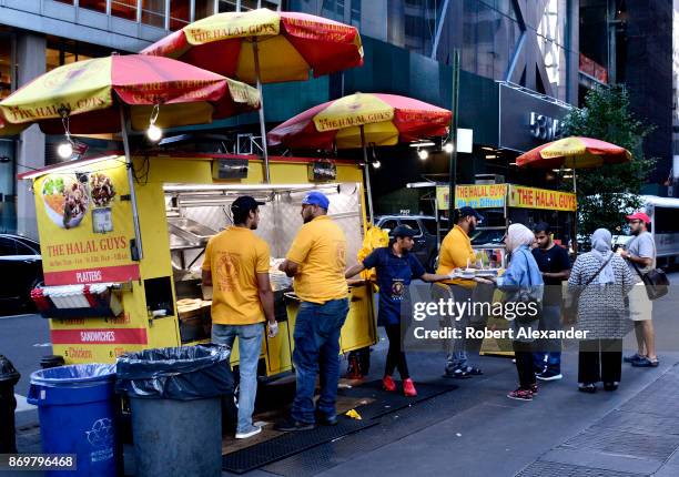 Customers purchase fast food lunches at food carts operated by The Halal Boys in New York, New York.