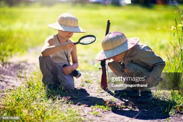 safari jongetjes beginnen vuur met vergroting glas - child with binoculas stockfoto's en -beelden
