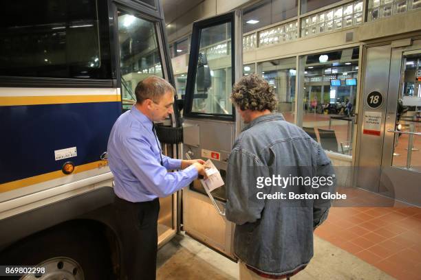 Plymouth & Brockton bus driver Stoyan Asenov checks a ticket before departing South Station in Boston on Nov. 1, 2017. With a shortage in the bus...