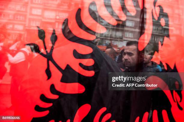 Kosovo Albanians seen through the Albanian national flag take part in a demonstration in Pristina, on November 3 to protest against the verdict of...