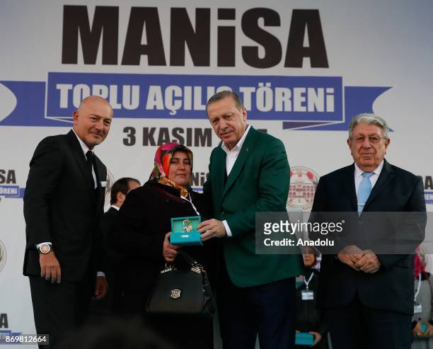 Turkish President Recep Tayyip Erdogan and Chairman of Turkey's Dogus Holding Ferit Sahenk gives a key of a house for relatives of victims who lost...