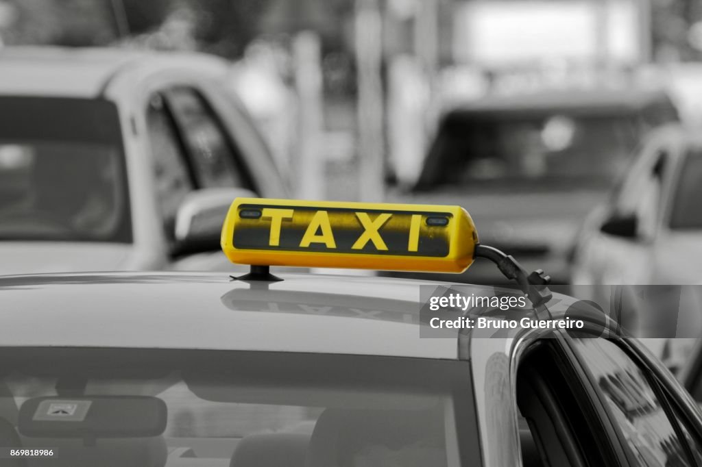 Close-up view of taxi sign against blurred traffic
