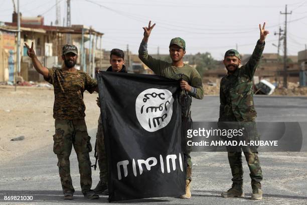 Iraqi members of the Hashed al-Shaabi carry an upsidedown Islamic State group flag in the city of al-Qaim, in Iraq's western Anbar province near the...