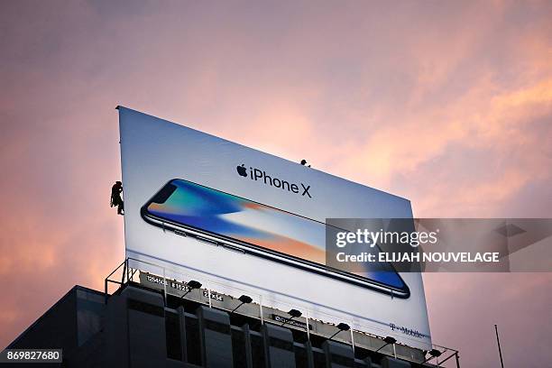 Workers finish putting up a new iPhone X billboard above Union Square in advance of the iPhone X launch on November 3 in San Francisco, California....