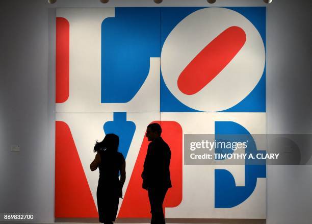 People walk past the art of Robert Indiana titled "The Great American Love " during a press preview at Sotheby's New York November 03, 2017 for the...