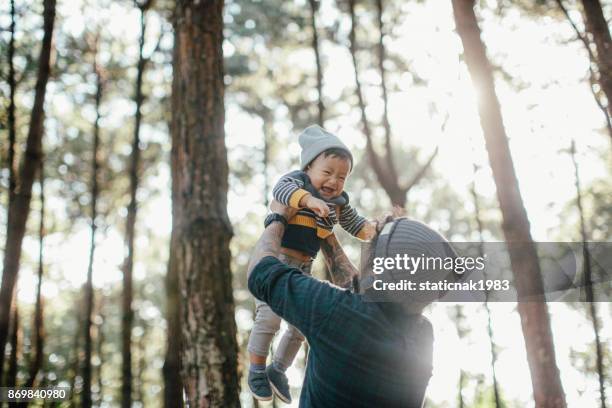 vater hält seinen sohn im wald bei sonnenuntergang. - baby lachen natur stock-fotos und bilder