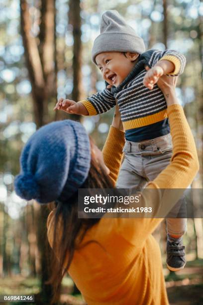 mother holding his son in forest in sunset. - asian toddler stock pictures, royalty-free photos & images
