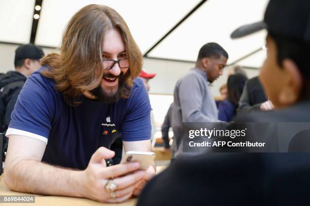 An Apple employee holds the new iPhone X while speaking to as young boy at the Apple Store Union Square on November 3 in San Francisco, California....