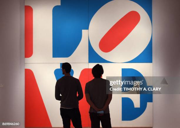 People walk past the art of Robert Indiana titled "The Great American Love during a press preview at Sotheby's New York on November 3, 2017 for the...