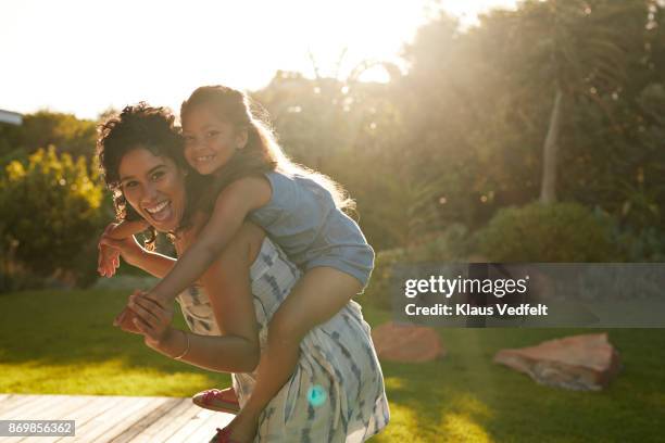 mother and daughter playing and laughing in their garden - piggyback stock pictures, royalty-free photos & images