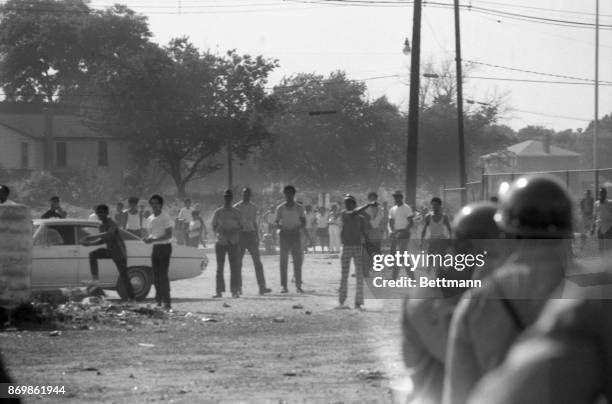 The man at right throws a rock at the policeman while the youngster near the car gets ready to do the same, during the July 7th afternoon disorders...