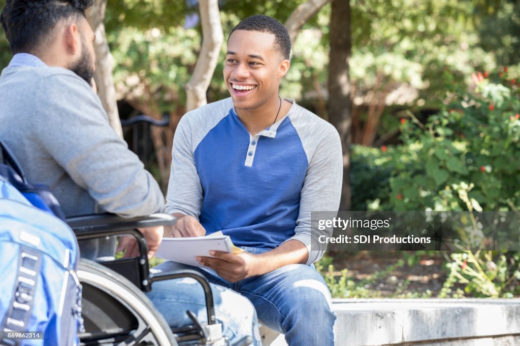 Young university student enjoys studying with wheelchair bound friend