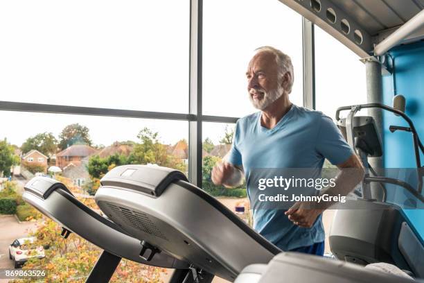 senior hombre usar la caminadora en el gimnasio con camiseta azul - treadmill fotografías e imágenes de stock