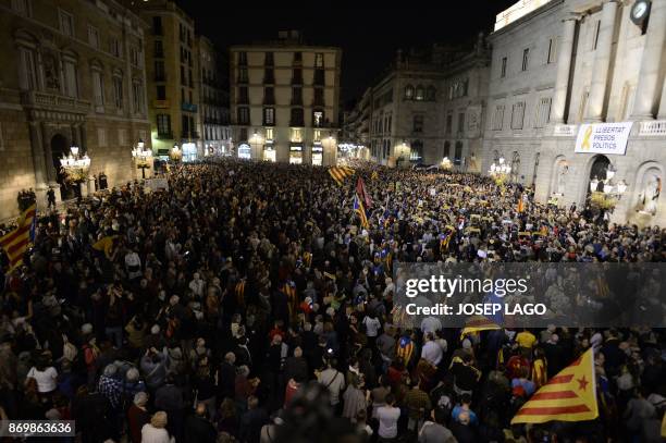 Banner reading "Freedom to political prisoners" hangs from the City Hall in Barcelona as protesters wave Catalan pro-independence Estelada flags...