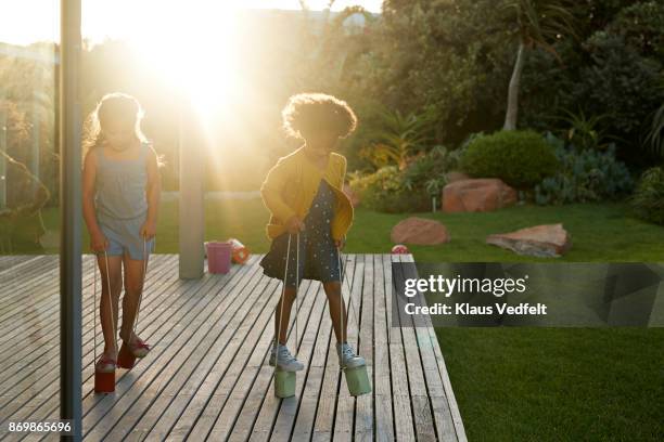 two girls walking with can stilts on wooden terrace - styltor bildbanksfoton och bilder