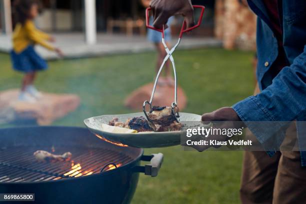 man flipping meat og the barbecue, at dusk - black plate stock pictures, royalty-free photos & images