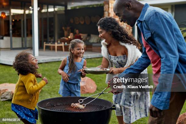 family cooking on grill in their garden - barbecue social gathering stock pictures, royalty-free photos & images
