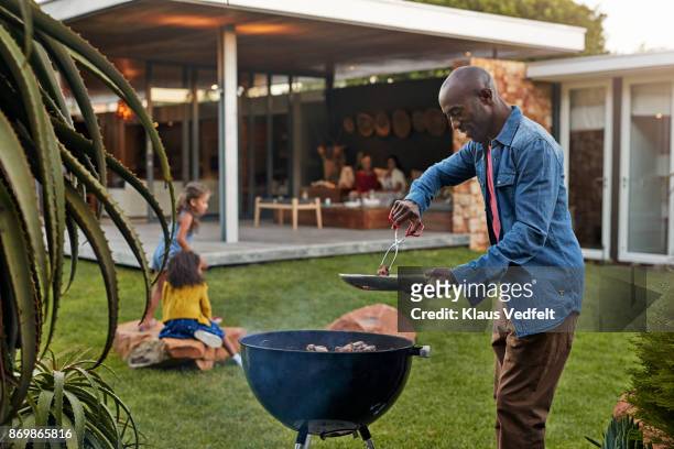 family cooking on grill in their garden - barbecue foto e immagini stock