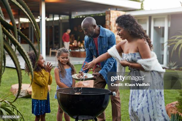 family cooking on grill in their garden - bbq father stock-fotos und bilder