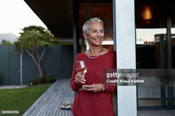 senior woman enjoying a glass of wine and the evening light - drinking alcohol at home stock pictures, royalty-free photos & images