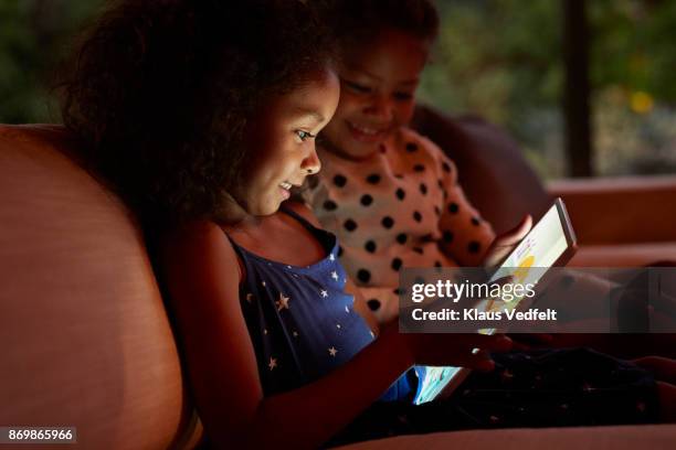 two young girls playing on digital tablet, at night - players to watch stock-fotos und bilder