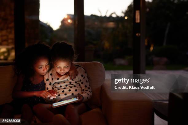 two young girls playing on digital tablet, at night - game six stockfoto's en -beelden