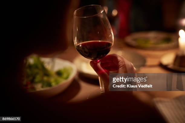 close-up of hand holding wine glass, at late dinner - senior women wine stock pictures, royalty-free photos & images