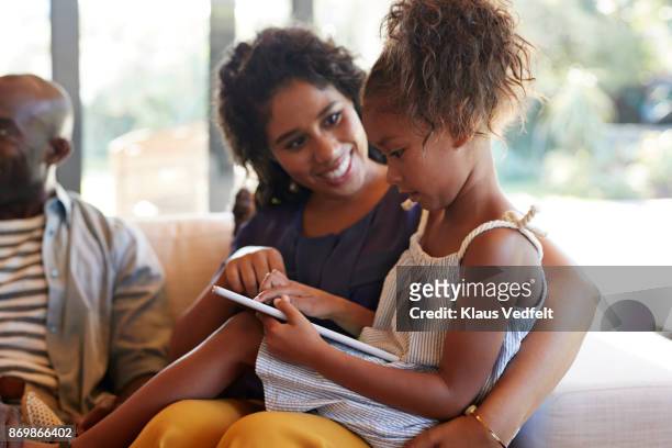 young girl playing drawing game on digital tablet, with grandmother - mother 2017 film stock pictures, royalty-free photos & images