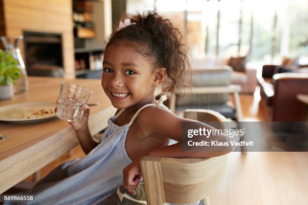 girl smiling to camera and holding glass of water - kid leaning stock pictures, royalty-free photos & images