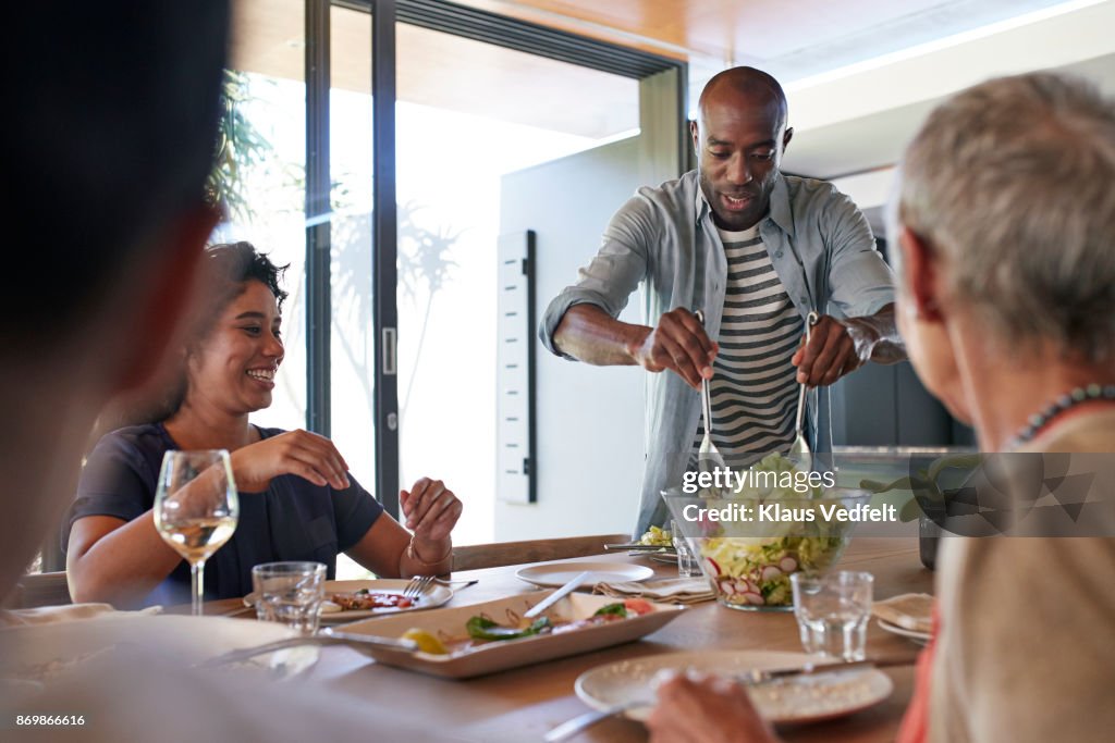 Man carrying salad to the table at family lunch