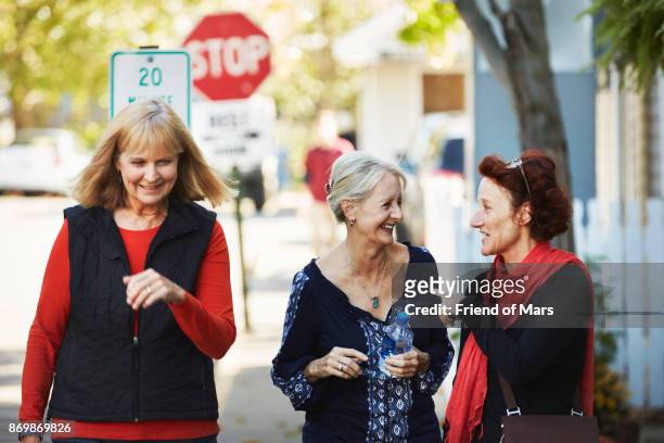 three senior women walk down the street and talk - localidad pequeña fotografías e imágenes de stock