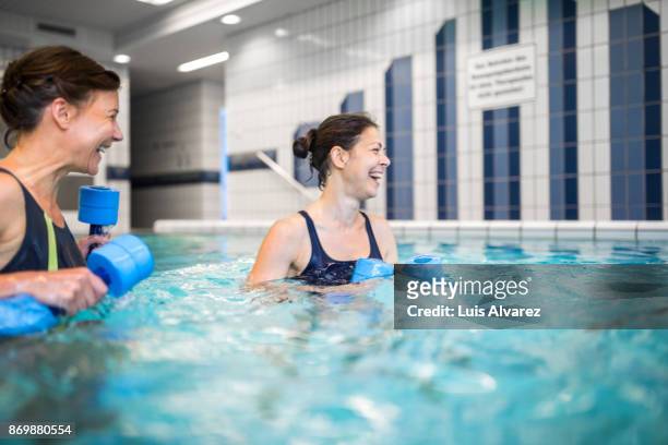 cheerful mature females with dumbbells in swimming pool - aqua aerobics stockfoto's en -beelden