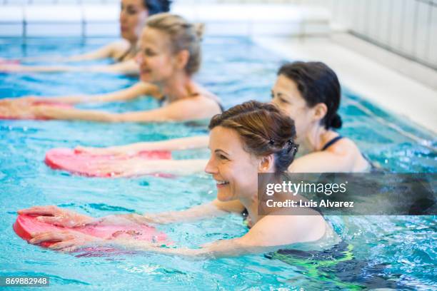 happy mature females exercising in swimming pool - aquarobics stock-fotos und bilder