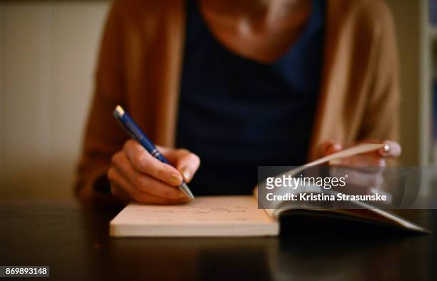 woman writing in a note book - authors fotografías e imágenes de stock