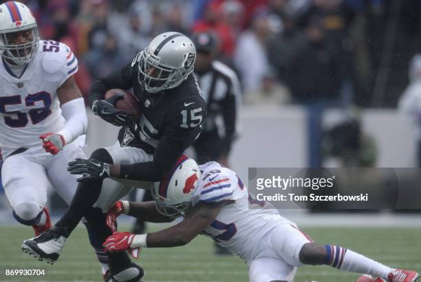 Michael Crabtree of the Oakland Raiders is hit by Shareece Wright of the Buffalo Bills as he carries the ball during NFL game action at New Era Field...