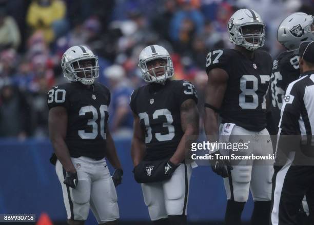 Jalen Richard of the Oakland Raiders and DeAndre Washington and Jared Cook watch a replay on the scoreboard during a break in the action during NFL...