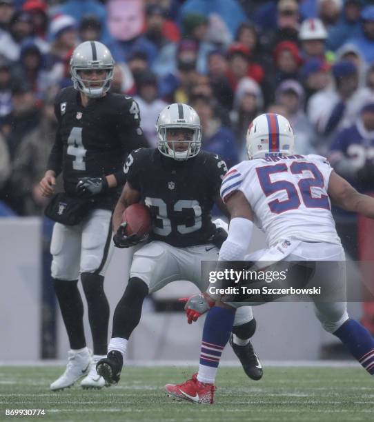 DeAndre Washington of the Oakland Raiders runs with the ball as Derek Carr watches during NFL game action against the Buffalo Bills at New Era Field...