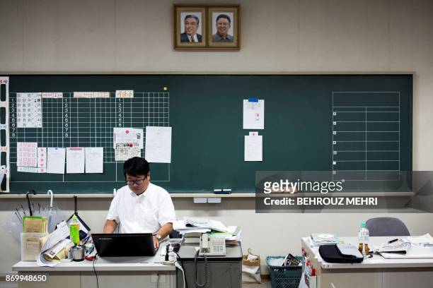In this picture taken on October 13 a teacher works with his laptop under portraits of late North Korean leaders Kim Il Sung and Kim Jong Il in...