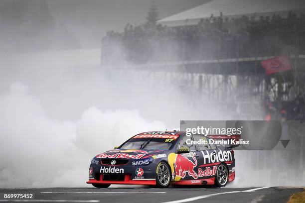 Shane Van Gisbergen drives the Red Bull Holden Racing Team Holden Commodore VF celebrates with a burnout after winning race 23 for the Auckland...