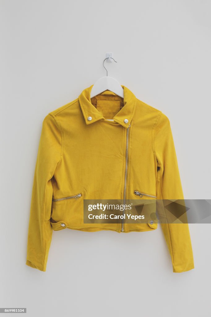 Yellow jacket hung on rack in diy fashion studio workshop space