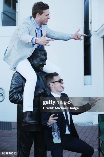 Racing fans plays around with the Bart Cummings statue after the last race on Derby Day at Flemington Racecourse on November 4, 2017 in Melbourne,...