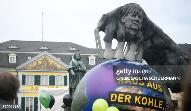 Environmentalists hold up an Earth-shaped balloon reading "Out of Coal" and decorated with an effigy of German Chancellor Angela Merkel seen in the...