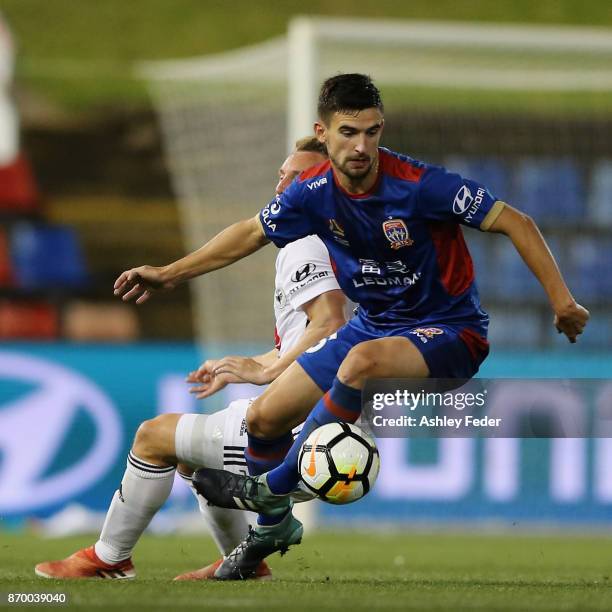 Steven Ugarkovic of the Jets is contested by the Phoenix defence during the round five A-League match between the Newcastle Jets and the Wellington...