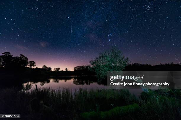 loughrigg tarn and a shooting star. lake district national park. uk. - loughrigg fells stock-fotos und bilder